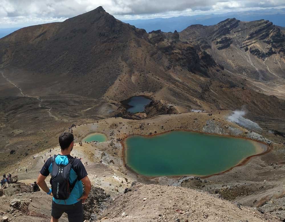 Visitar Nueva Zelanda chico moreno de espaldas mirando un volcán